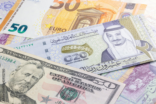 Close up 20 Riyals of Saudi Arabia between 50 US Dollar and 50 Euro banknotes. Twenty Riyal banknotes of the Arabic country. Money of the US and Europe with Saudi Riyal banknote. G20 summit banknote photo