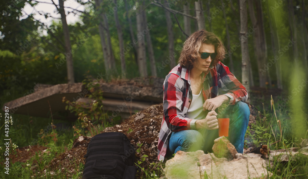 Man sits in front of bonfire in the forest. Man sits in front of bonfire in the forest.