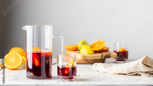 Crystal Jug and glass with Sangria drink, famous Spanish summer beverage  on the table with ingridients.