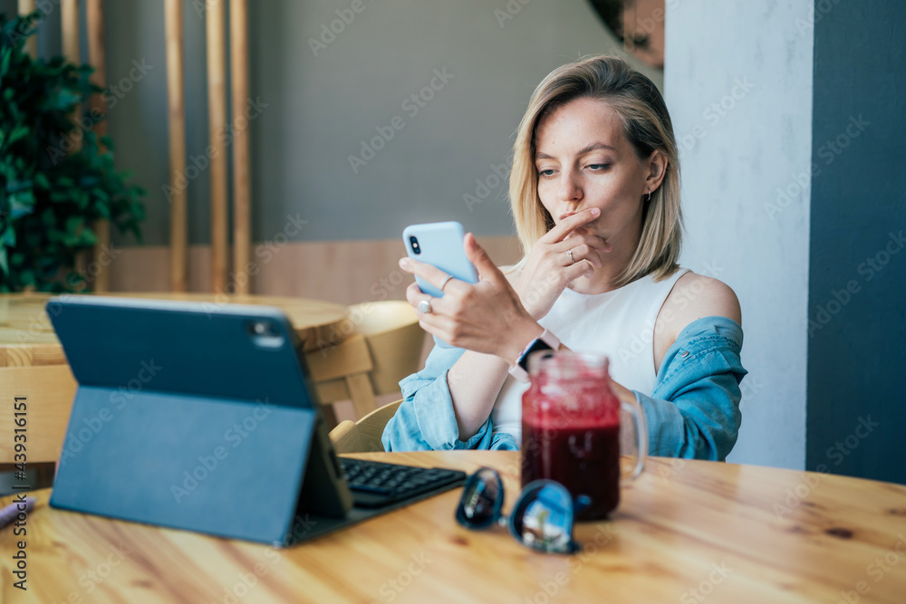 Young concentrated businesswoman working on laptop and mobile phone