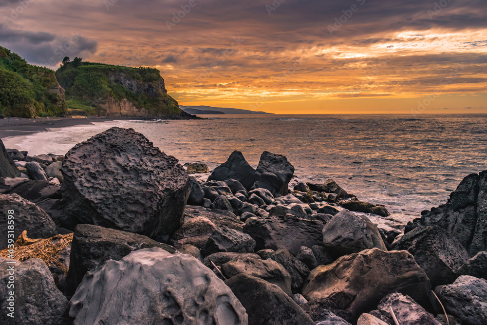 Selective focus on black and volcanic rocks with colorful sunset at Viola beach, São Miguel - Azores PORTUGAL