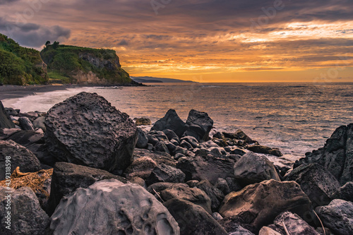 Selective focus on black and volcanic rocks with colorful sunset at Viola beach, São Miguel - Azores PORTUGAL