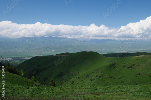 green hill slope under sunlight shadow. White clouds in blue skyline. At Nalati prairie in Xinjiang China