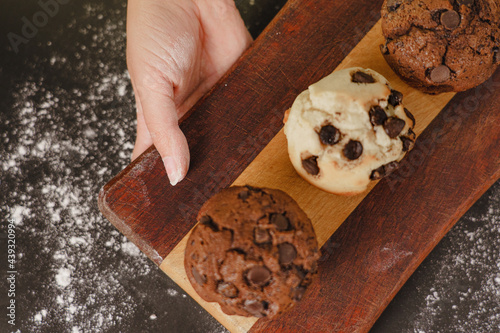pastry chef presenting homemade vanilla and chocolate chips muffins  on a black background with sugar