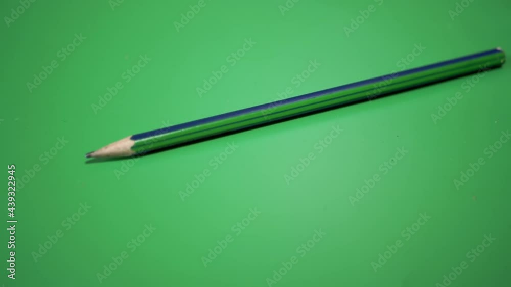 Simple Pencil for Drawing, Falls, Rolls over a Green Background. The concept of teaching drawing, writing, sketching. Slow motion. Close up. Slow-motion. 180 fps. Simple Pencil for Drawing, Falls, Rolls over a Green Background. The concept of teaching drawing, writing, sketching. Slow motion. Close up. Slow-motion. 180 fps.