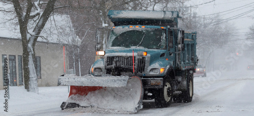 Municipal snowplow clearing Mains street during a snow storm