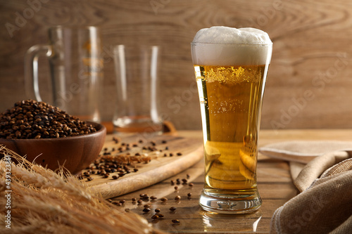 Beer in the glass and malt on wooden table background. Alcohol drink concept.