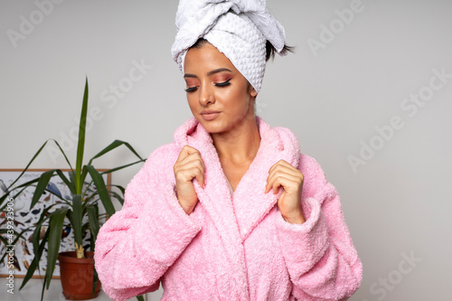 Happy young woman in pink bathrobe and wrapped towel on head relax in beauty studio
