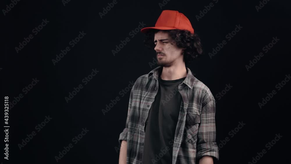 The disgusted young man with the red cap looks disgusted with his hands to one side as a sign of keeping his distance. Isolated on black background. The concept of life. People's emotions. 4k portrait The disgusted young man with the red cap looks disgusted with his hands to one side as a sign of keeping his distance. Isolated on black background. The concept of life. People's emotions. 4k portrait