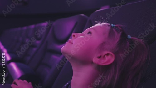 A little girl sitting in the planetarium auditorium looks up and laughs. photo