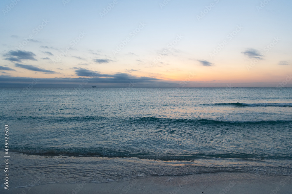 Early morning, sunrise over sea. Ocean sunset on sea water with sunset sky and silhouettes of ship.