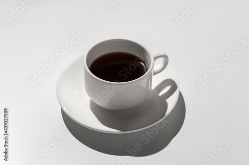 white coffee cup with espresso. hard shadows on gray background
