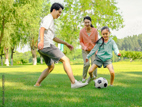 Happy family of three playing football in the park