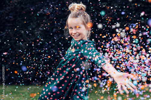 beautiful smiling little girl under a shower of confetti - birthday party carefree celebration concept