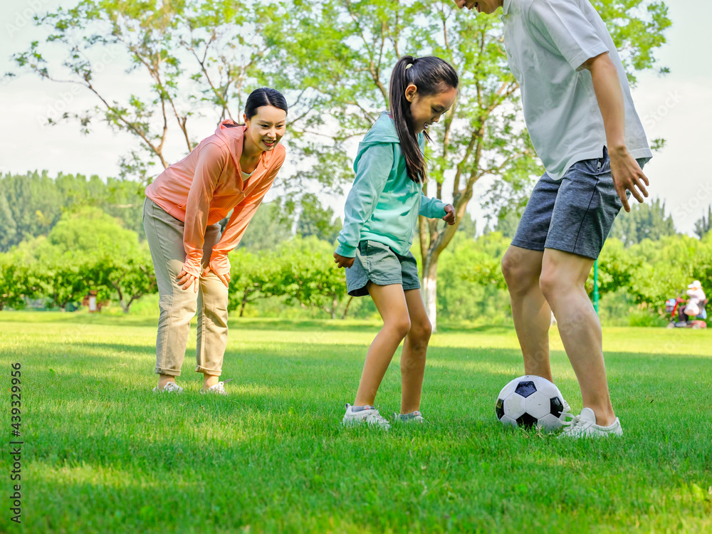 Obraz premium Happy family of three playing football in the park