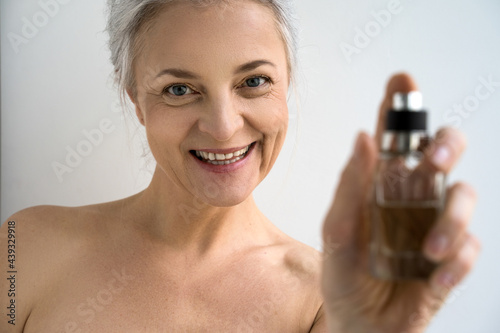 Woman with naked shoulders showing to the camera cosmetic container photo