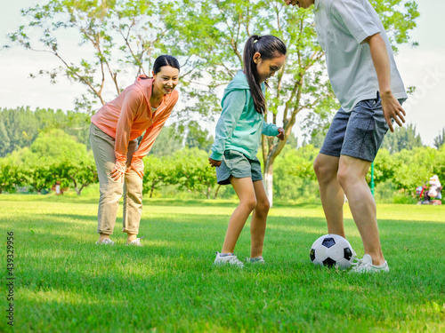 Happy family of three playing football in the park