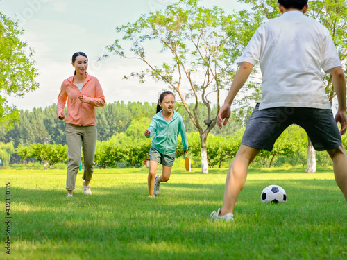 Happy family of three playing football in the park