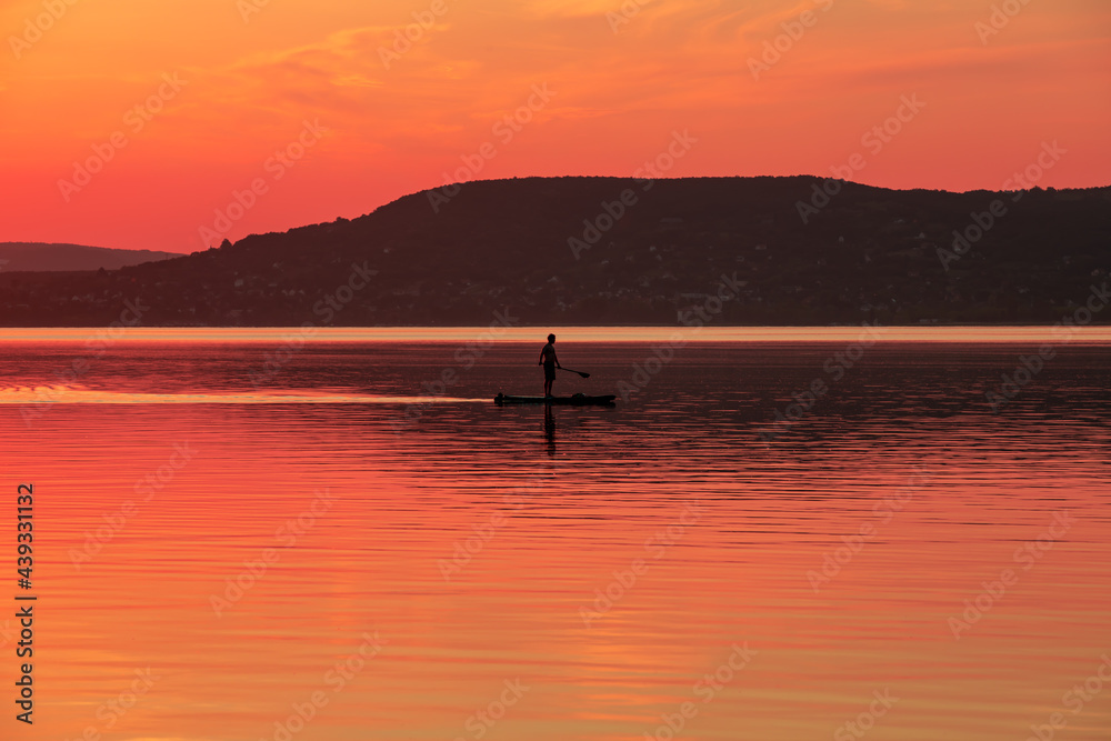 landscape with a man paddling on a raft in the evening at Lake Balaton - Hungary 