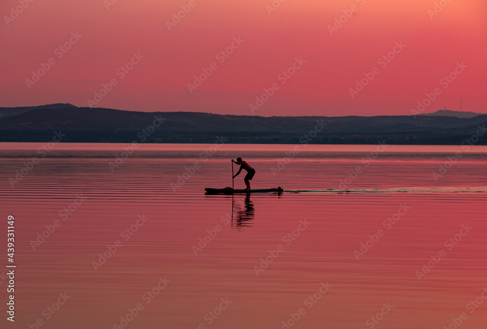 silhouette of a person rowing on the lake in the evening