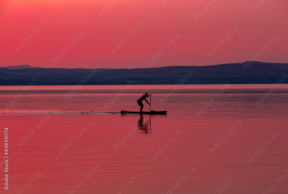 a man on a raft in the evening on the lake