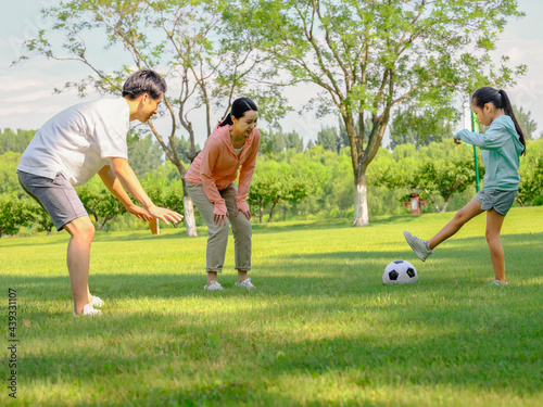 Happy family of three playing football in the park