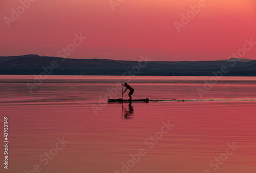 silhouette of a person rowing on the lake in the evening