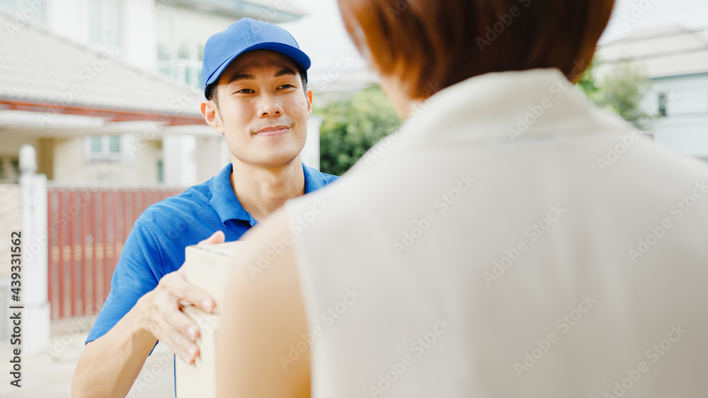 Obraz premium Young Asia postal delivery courier man in blue shirt handling parcel boxes for sending to customer at house and Asian female receive delivered package outdoors. Package shopping food delivery concept.