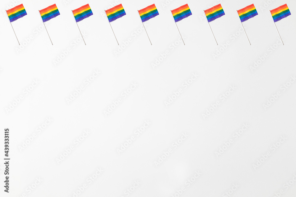 Obraz premium Lgtbi community rainbow flags pattern with hard shadow on white background. Pride day concept