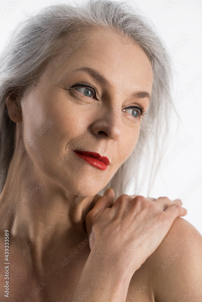 Fototapeta premium Aging woman touching her shoulder and smiling calmly