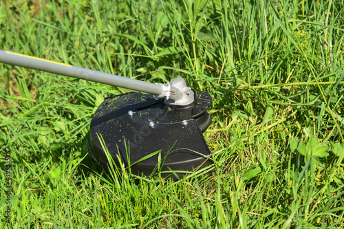 Electric trimmer mows grown grass on the lawn forming a circle. Trimmer close up mow the grass with a lawnmower. Gardening with a brush cutter Close-up. Lawn care with brush cutters.