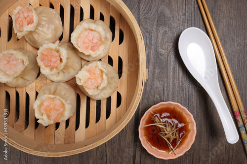 Prawn shrimp shaomai dim sum dumpling in bamboo steamer sauce chopsticks soup soon on rustic wood background photo