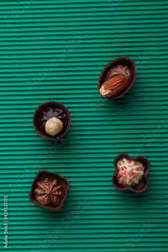 Assortment of brown pralines chocolate candies on green background.