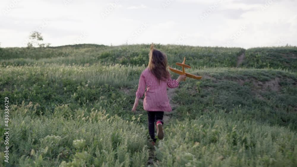 Happy child, girl, playing with a toy airplane on a summer field. A child runs away on the grass holding a toy airplane in his hands. My daughter dreams of flying. Carefree child playing outdoors. Happy child, girl, playing with a toy airplane on a summer field. A child runs away on the grass holding a toy airplane in his hands. My daughter dreams of flying. Carefree child playing outdoors.