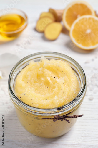 Body scrub in glass jar on white wooden table, closeup