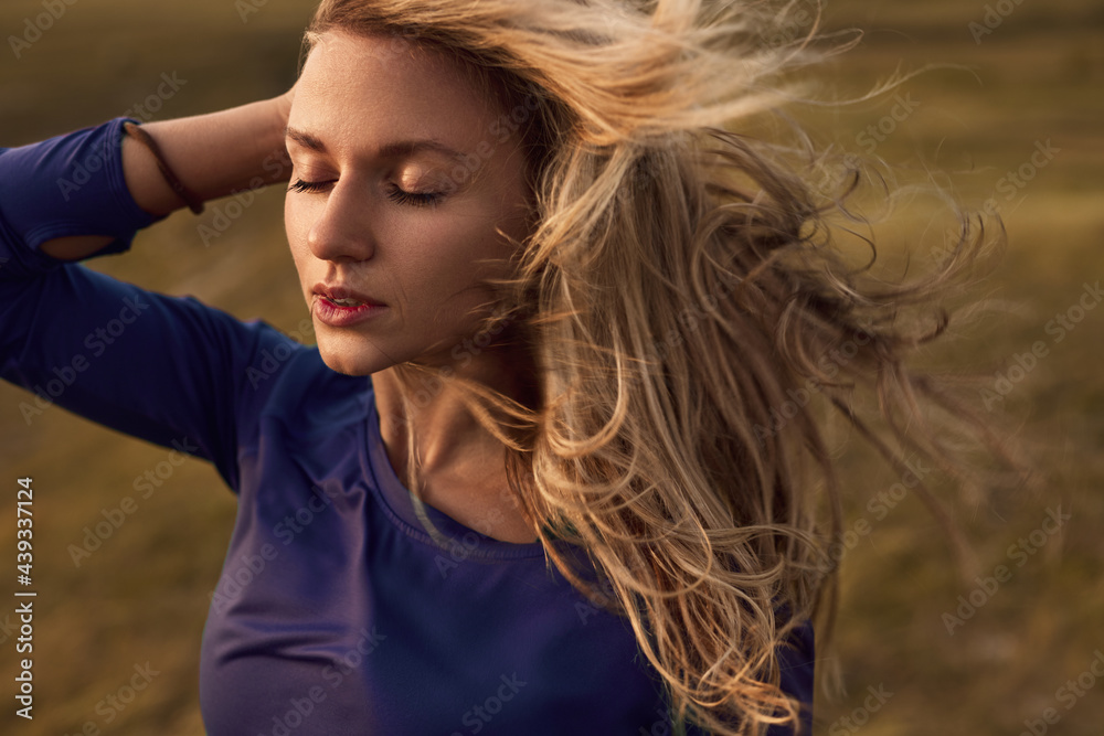 Young woman with flying hair in wind resting in nature Young woman with flying hair in wind resting in nature