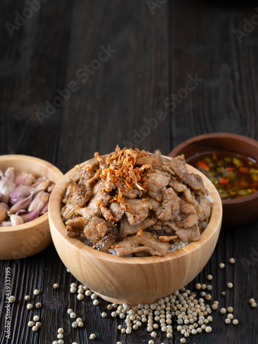 Thai food, Rice topped with pork and garlice in wooden bowl on brown wooden table. Favorite food in Thailand. photo