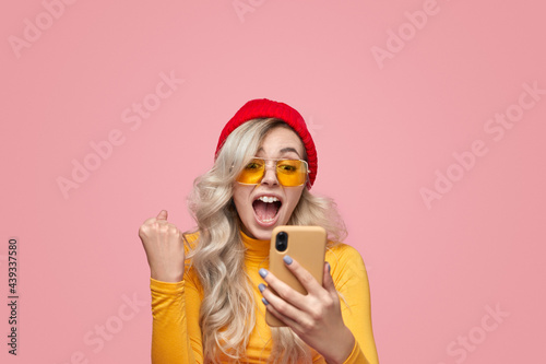 Excited woman with smartphone celebrating victory
