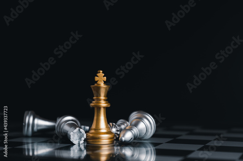 Gold king winner surrounded with silver chess pieces on chess board game competition.concept strategy, leadership and success business.