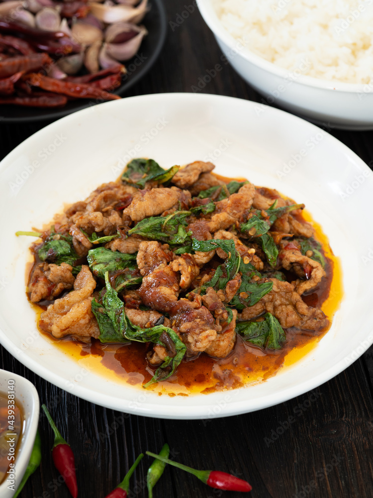 Thai food, Stir fried pork and basil in white plate on brown wooden table. Favorite food in Thailand. Thai food, Stir fried pork and basil in white plate on brown wooden table. Favorite food in Thailand.