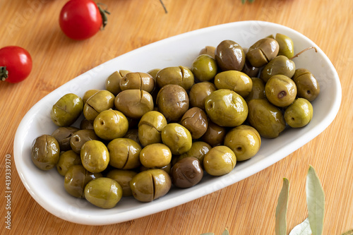 Green olive. Tasty scratched olive in the plate. Green olives on wooden background
