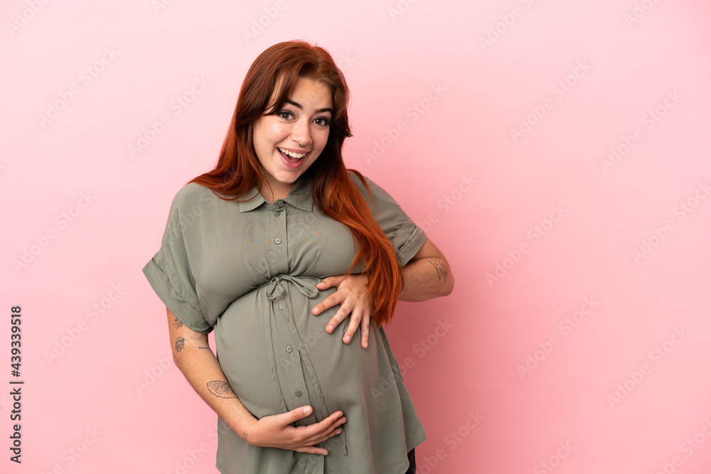 Young redhead caucasian woman isolated on pink background pregnant and doing surprise gesture Young redhead caucasian woman isolated on pink background pregnant and doing surprise gesture