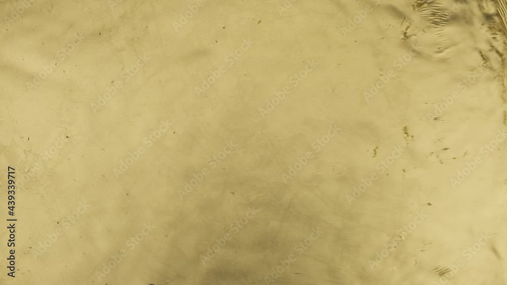 Slow motion. Gold wave top view. Abstract gold liquid illuminating yellow color oily waves. Horizontal motion. Flowing lines. Fluid texture. Copy space. Slow motion. Gold wave top view. Abstract gold liquid illuminating yellow color oily waves. Horizontal motion. Flowing lines. Fluid texture. Copy space.
