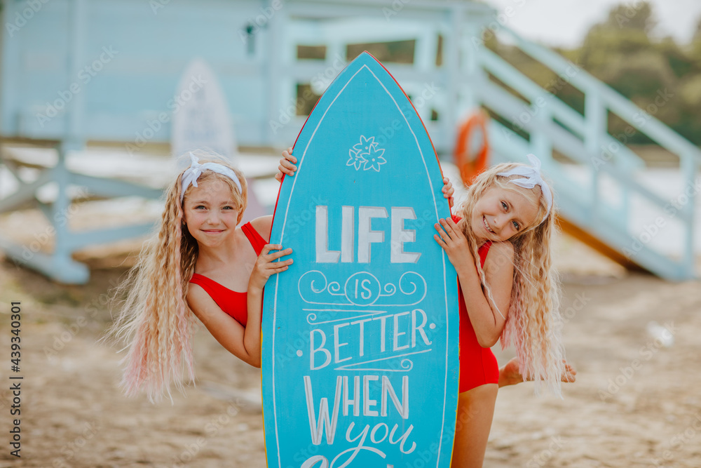 Girls in red bikini posing with surfboards against lifeguard tower on