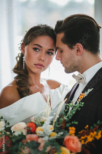 Close-up portraits of beautiful couple of newlyweds with bridal bouquet