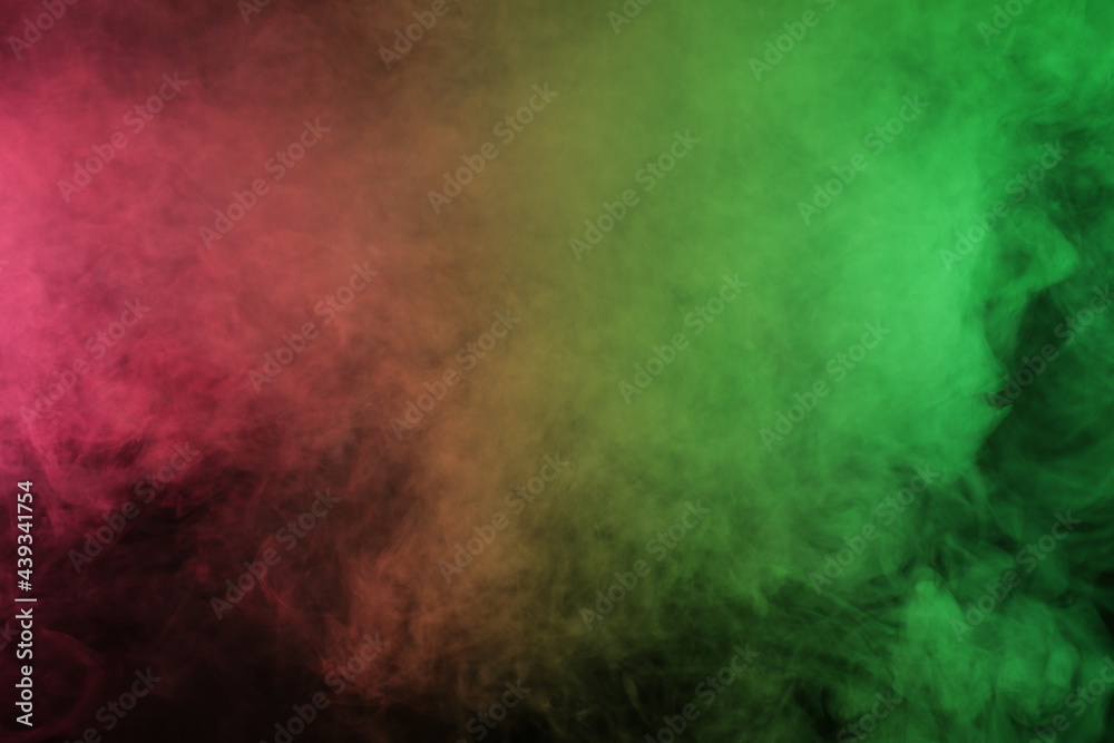 Obraz premium Artificial smoke in red-green light on black background