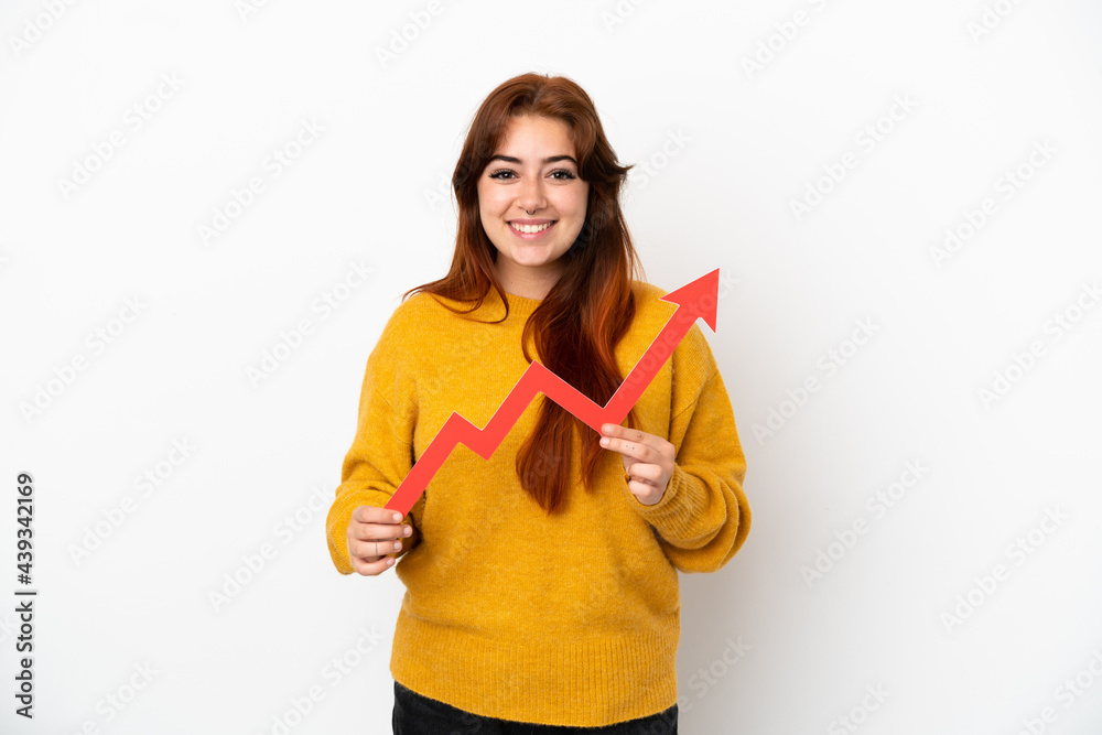 Young redhead woman isolated on white background holding a catching a rising arrow with happy expression Young redhead woman isolated on white background holding a catching a rising arrow with happy expression