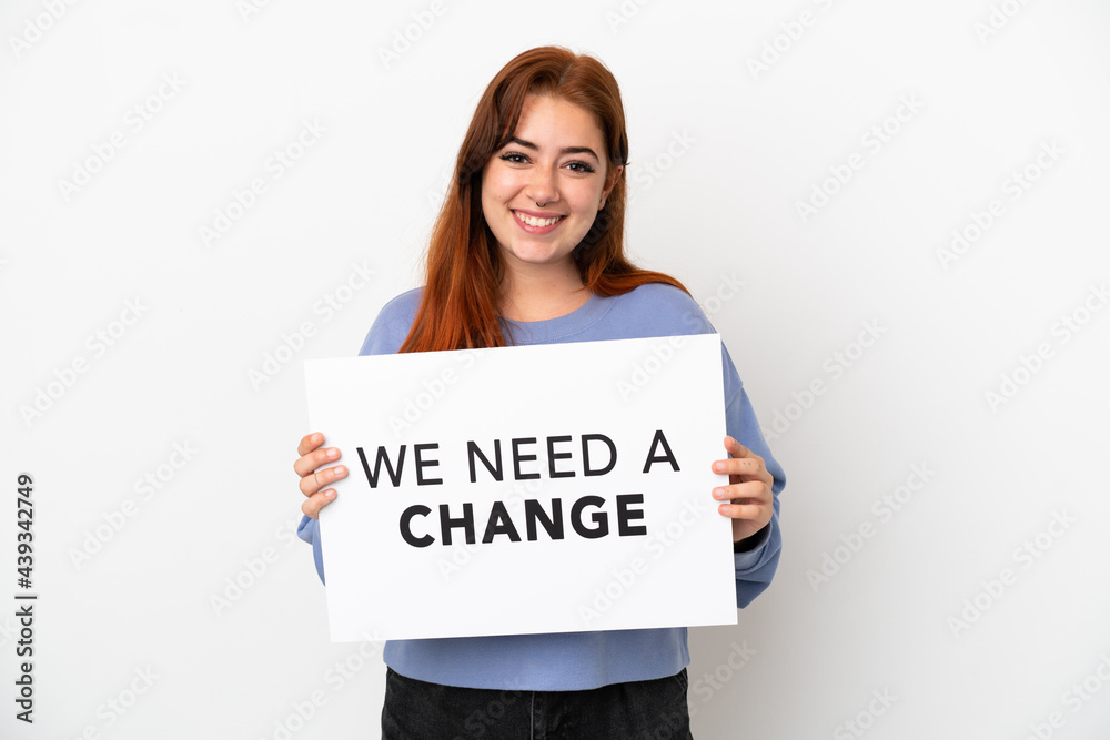 Young redhead woman isolated on white background holding a placard with text We Need a Change with happy expression Young redhead woman isolated on white background holding a placard with text We Need a Change with happy expression