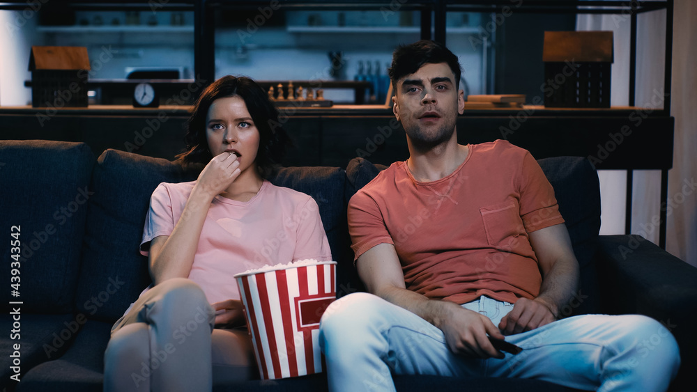 woman eating salty popcorn and watching movie with man at home. woman eating salty popcorn and watching movie with man at home.