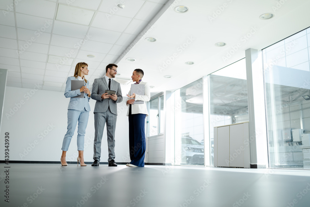Three business colleagues discussing work related matters on an office building hallway. Team work. Three business colleagues discussing work related matters on an office building hallway. Team work.